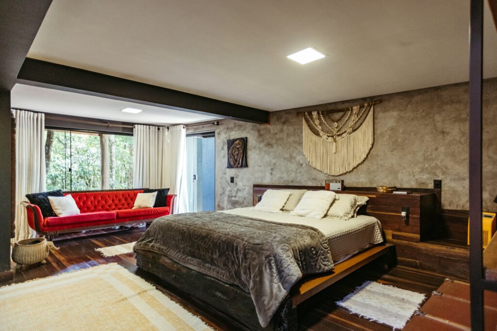 A bedroom with a large bed and a red couch
