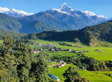 a scenic view of a green valley with mountains in the background